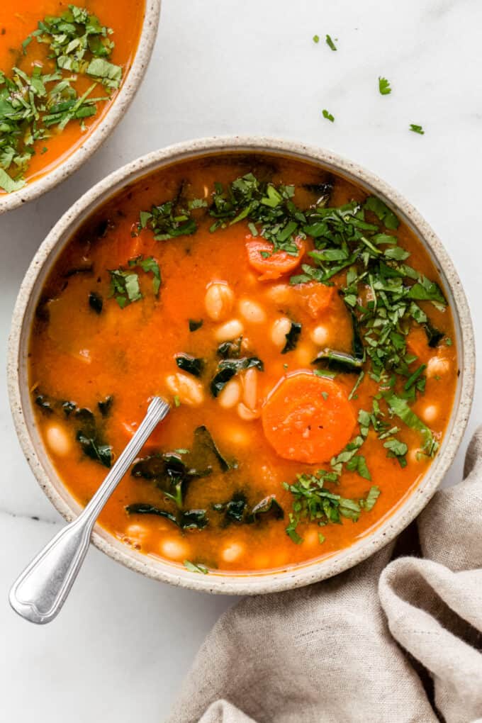 white bean and kale soup topped with chopped parsley