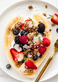 breakfast banana split with yogurt and berries on a plate