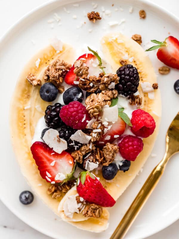 breakfast banana split with yogurt and berries on a plate