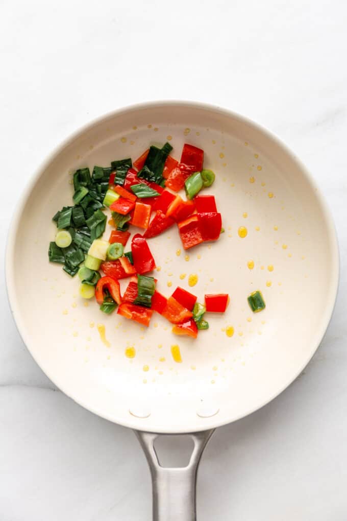 green onions and red peppers in a pan