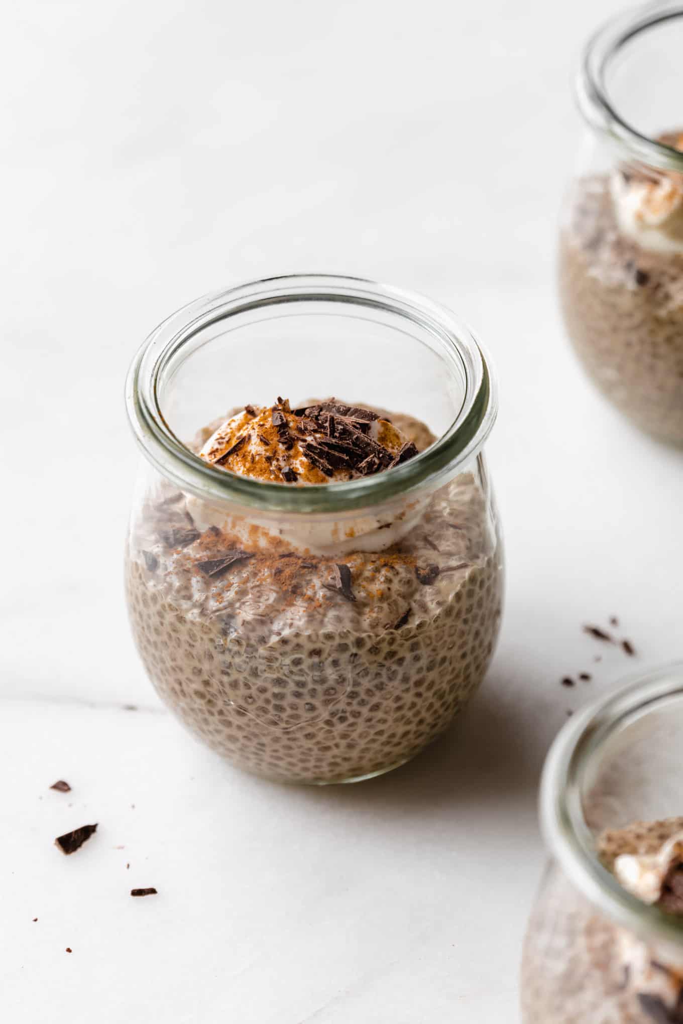 a jar of coffee chia pudding topped with yogurt, cinnamon and chocolate