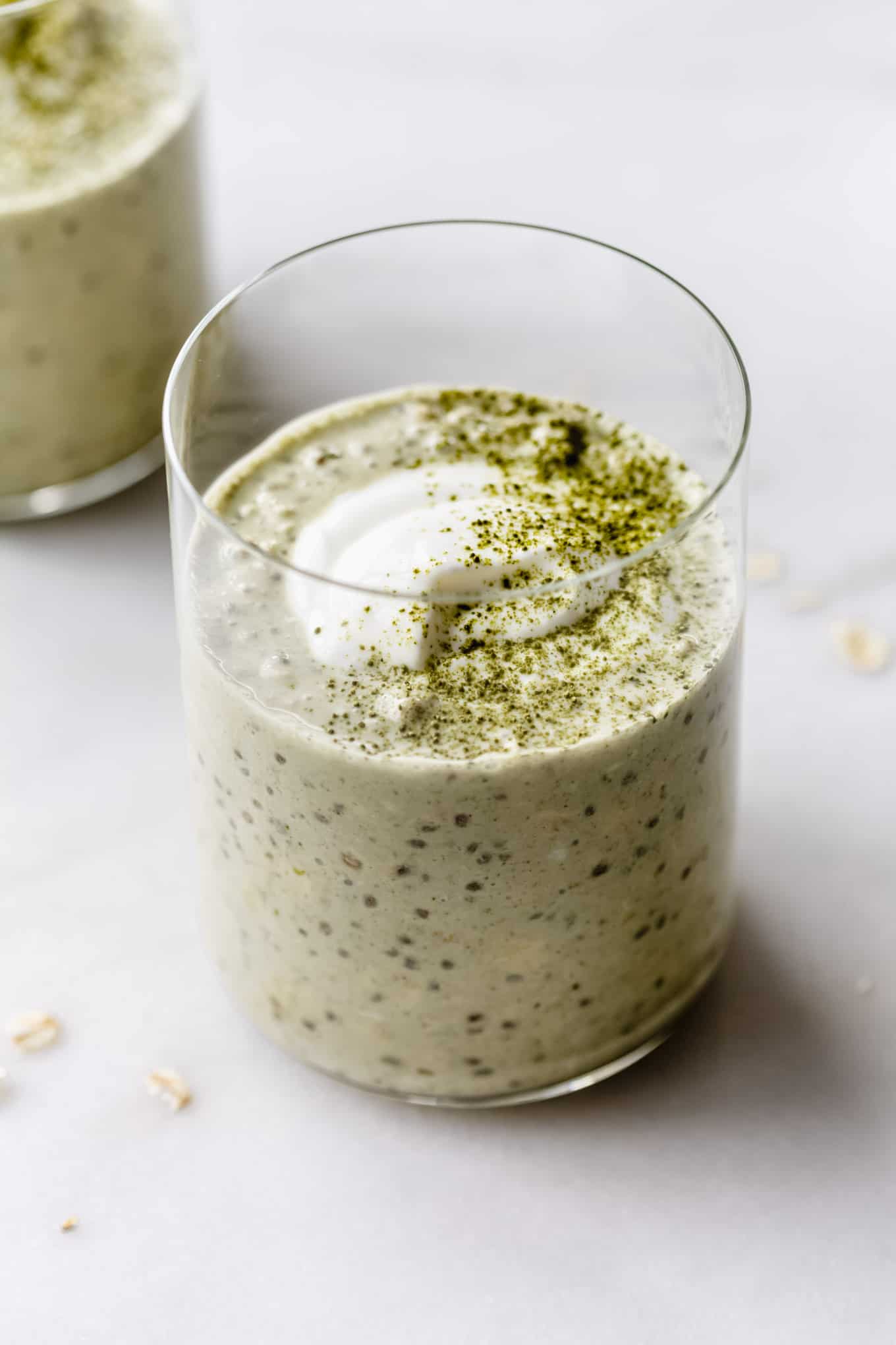 a cup of matcha overnight oats topped with yogurt and matcha powder