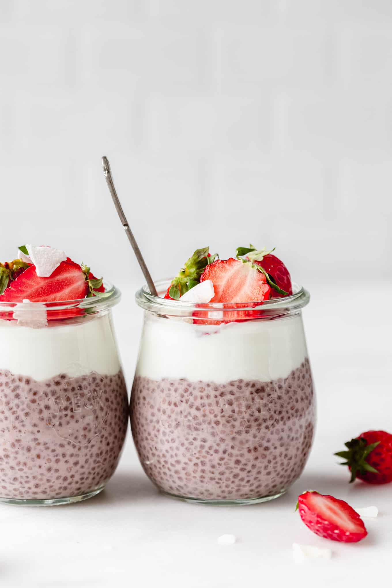 two jars of strawberry chia seed pudding topped with strawberries