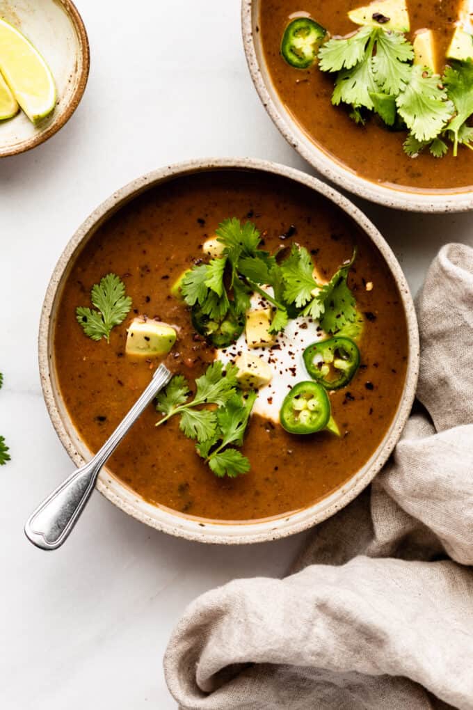 two bowls of black bean soup with a beige napkin on the side