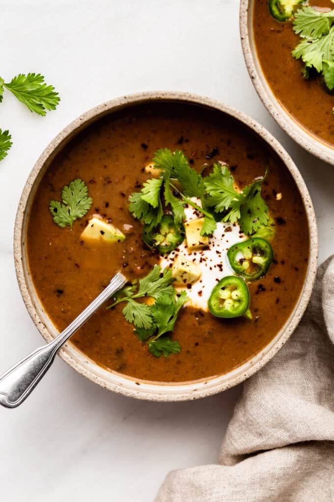 a bowl of black bean soup with cilantro, sour cream and avocado