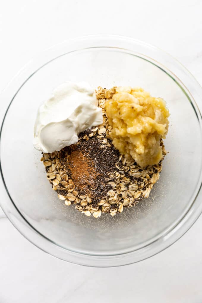 oats, chia seeds, nutmeg, yogurt and banana in a mixing bowl