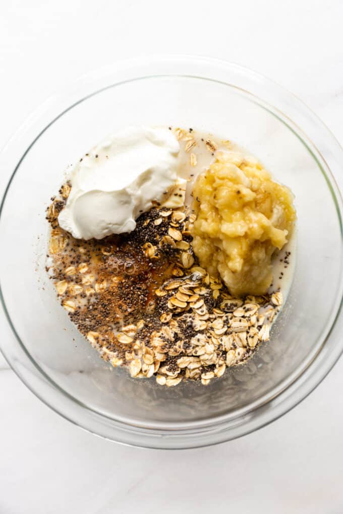oats, chia seeds, nutmeg, yogurt, bananas and almond milk in a mixing bowl