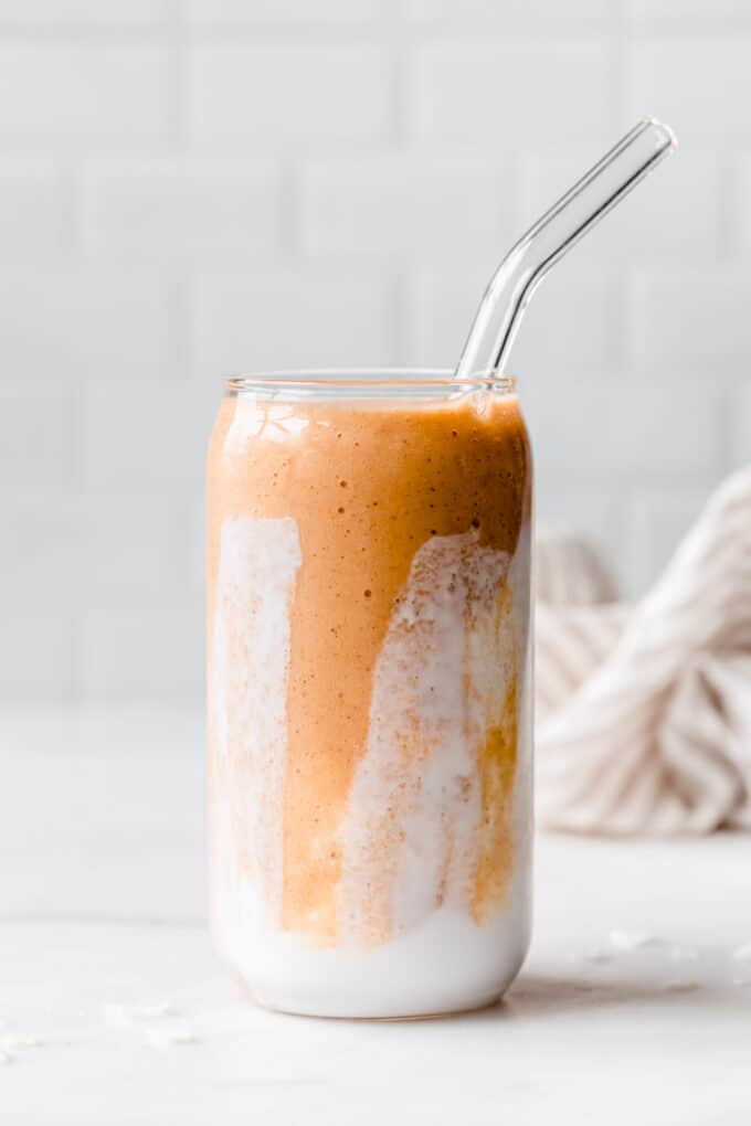 a papaya smoothie in a glass with a glass straw
