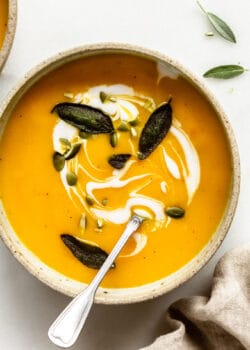 roasted acorn squash soup in a bowl with sage, pumpkin seeds and coconut milk