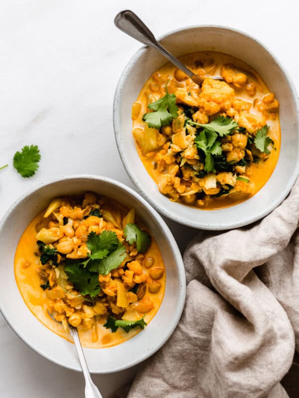 two bowls of coconut cauliflower curry topped with cilantro