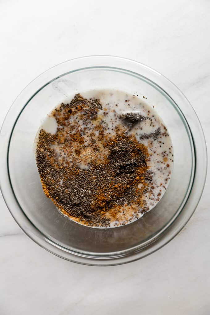 chia seeds, coconut milk and spices in a clear mixing bowl