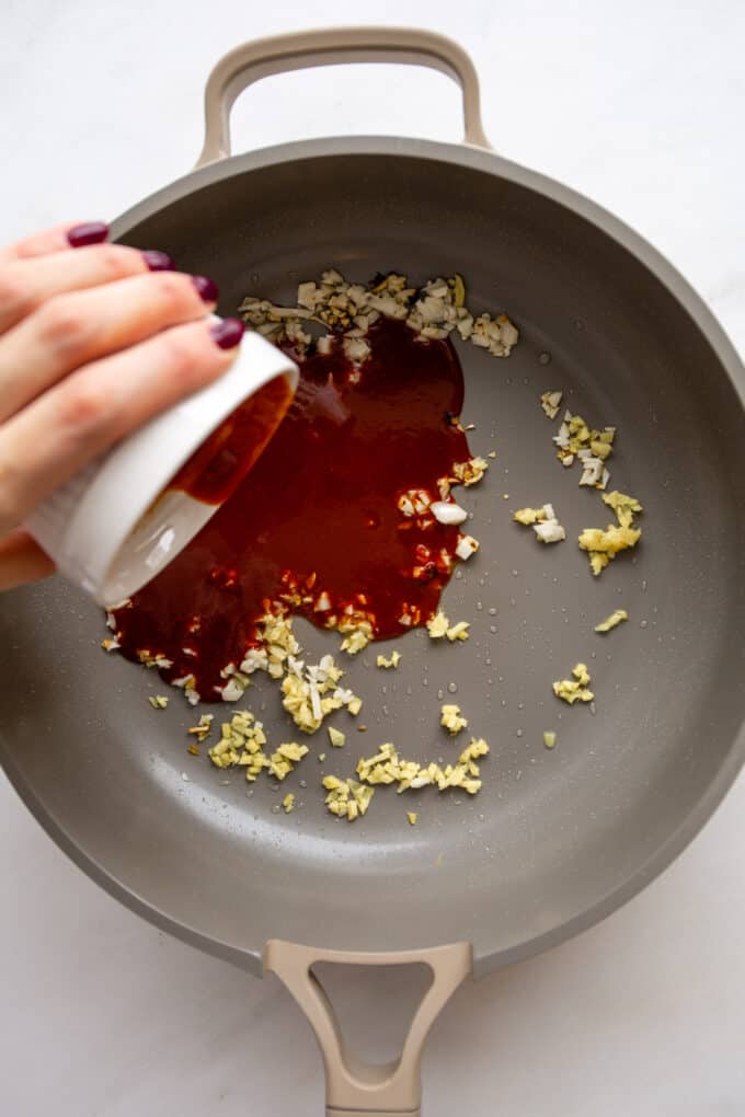 gochujang sauce being poured into a pan