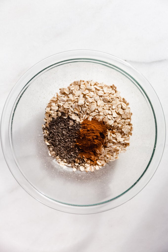 oats, chia seeds and cinnamon in a clear mixing bowl.