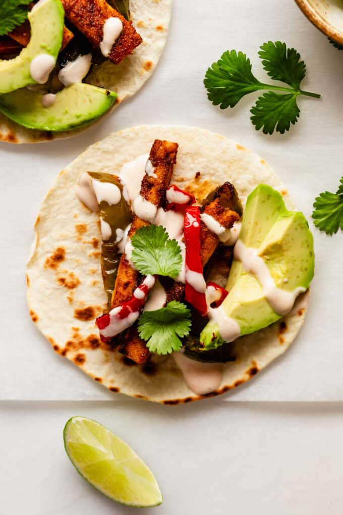 a tofu fajita with avocado and chipotle crema on a taco shell
