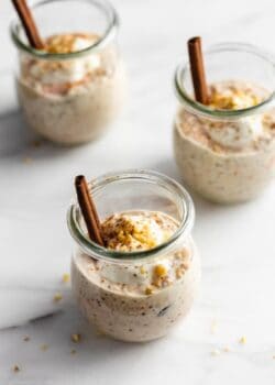 carrot cake overnight oats in 3 jars topped with yogurt and walnuts