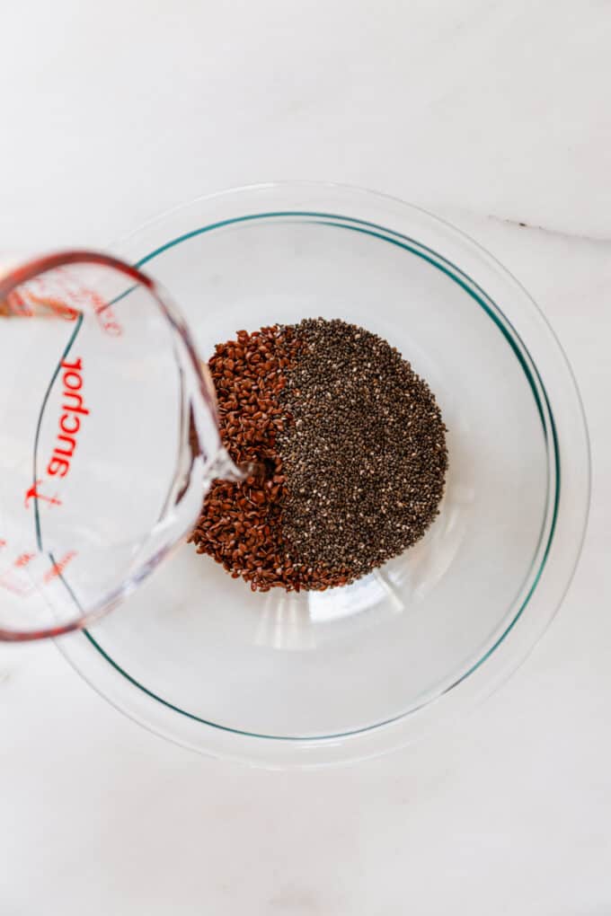 water being poured into a mixing bowl of chia and flax seeds
