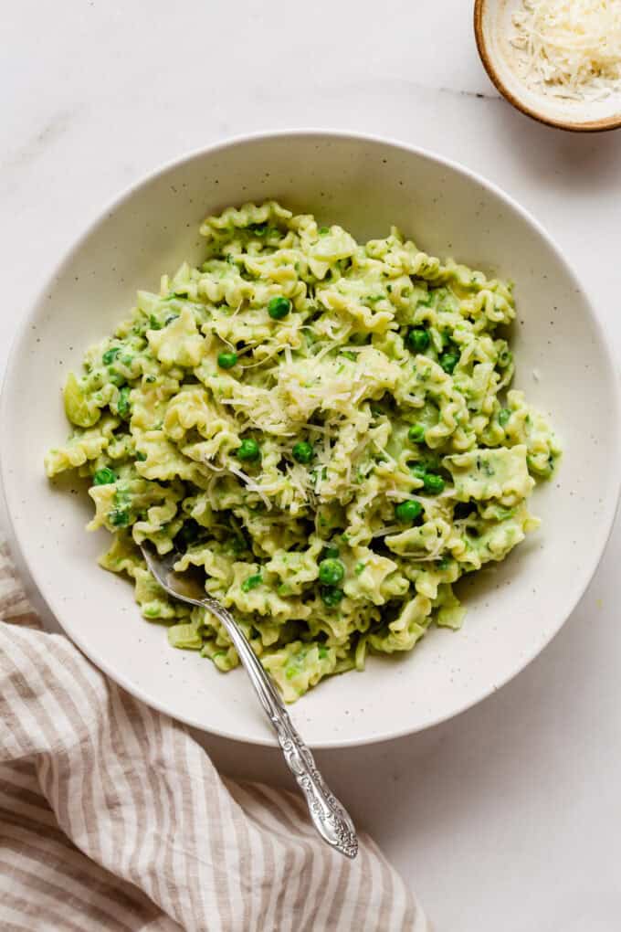 ricotta and pea pata in a bowl with a fork and a napkin on the side