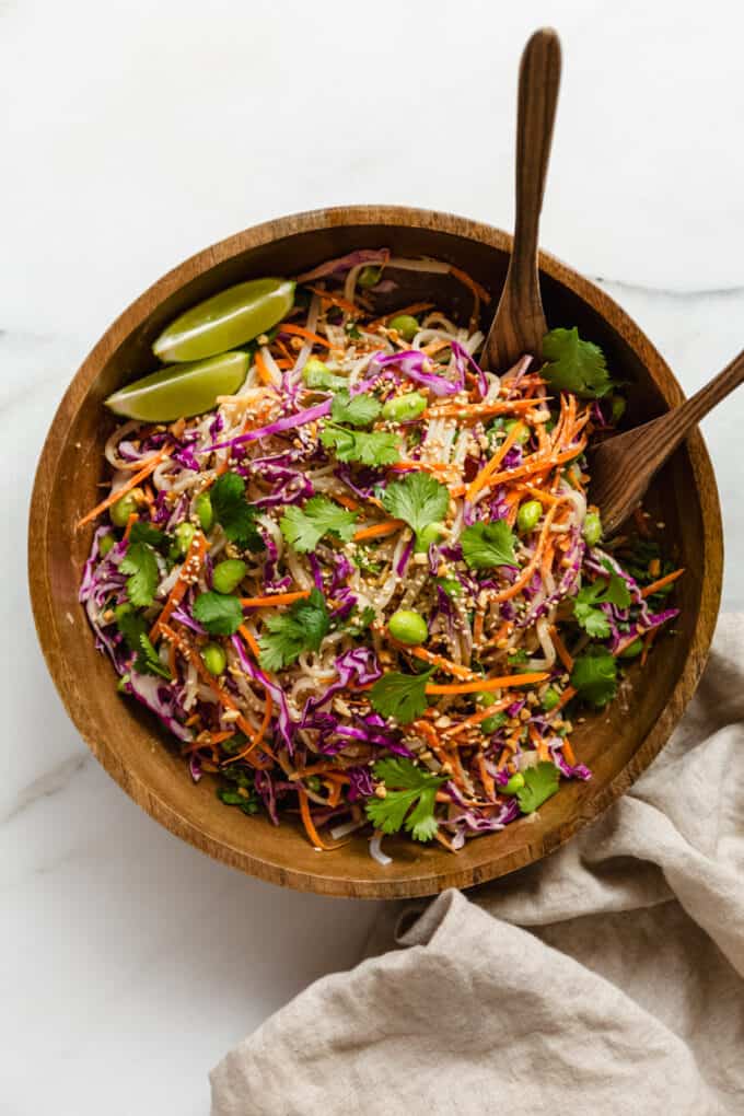 a wooden bowl with wooden spoons with a Thai noodle salad in it