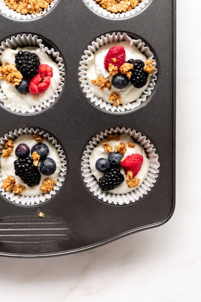 muffin tin filled with yogurt, berries and granola