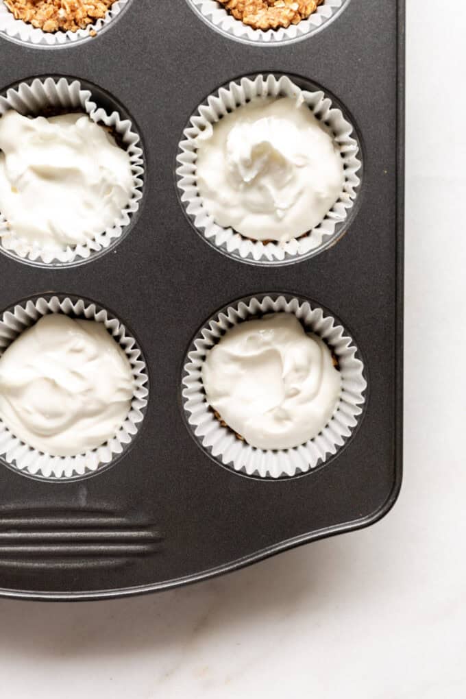 yogurt on top of granola crust in a muffin tin