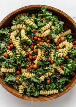 a kale caesar pasta salad in a wood mixing bowl
