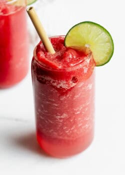 a watermelon slushie with a lime slice and bamboo straw