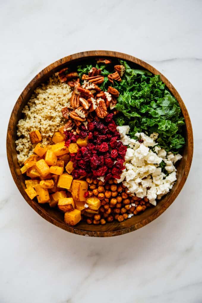 roasted butternut squash, quinoa, chickpeas, feta, kale, pecans and dried cranberries in a wood bowl