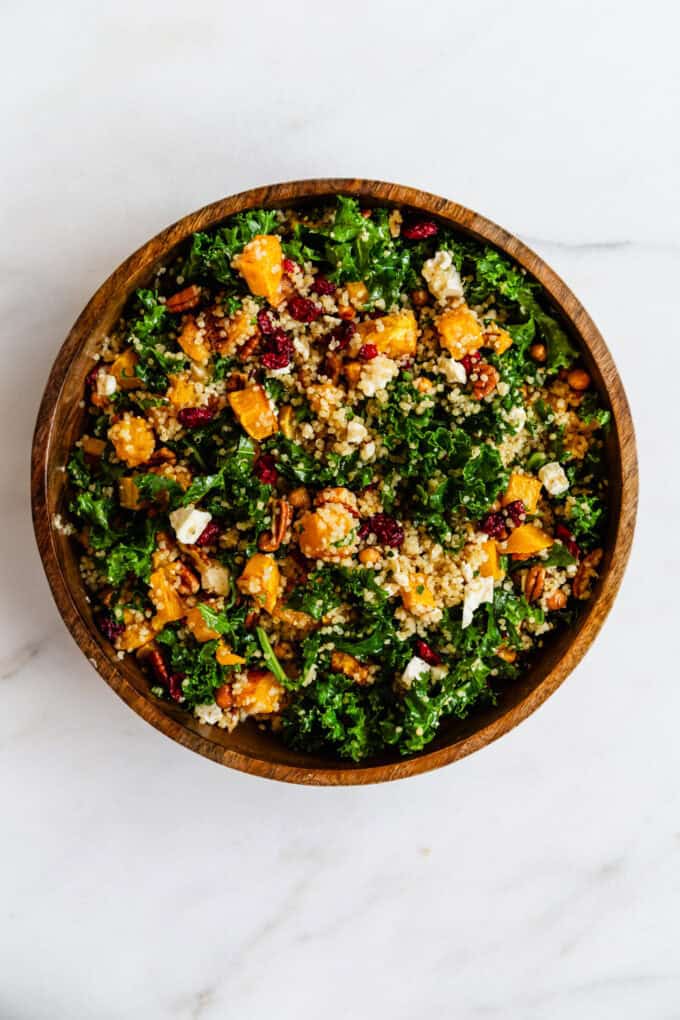 a butternut squash and kale salad in a wood serving bowl