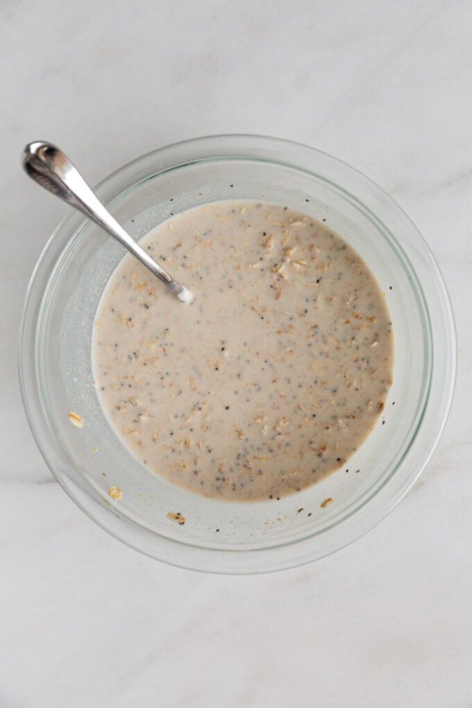 un-chilled overnight oats ingredients in a clear mixing bowl with a spoon