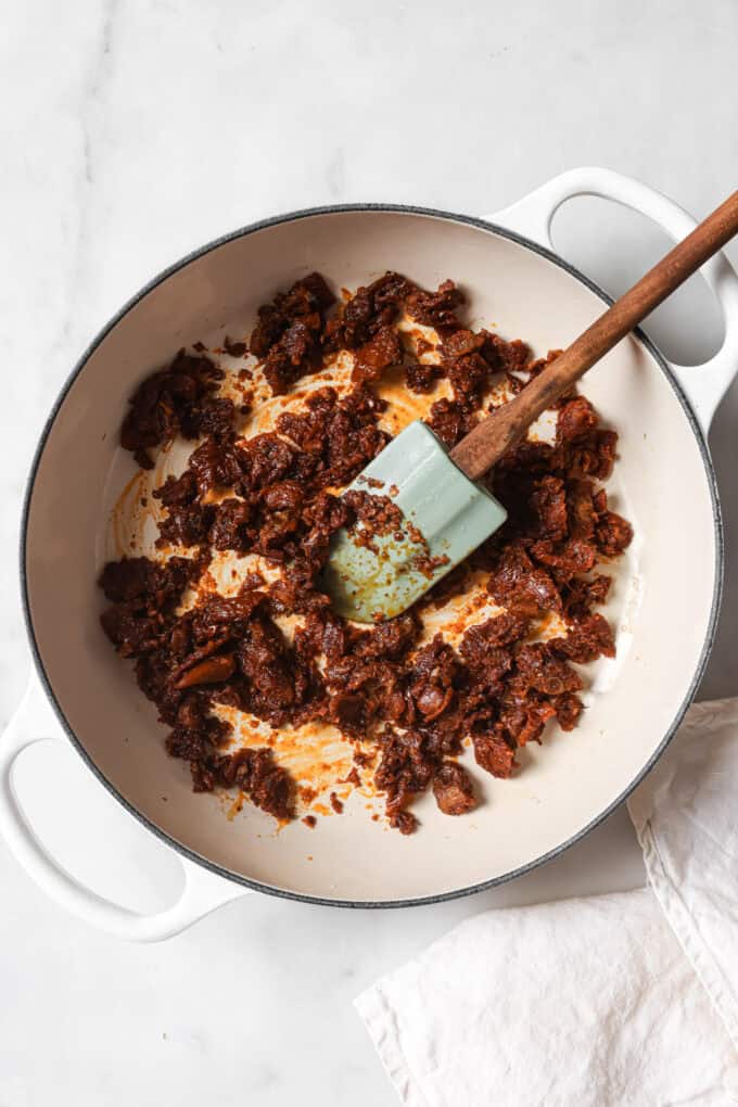 sundried tomatoes in a white pot with a spatula