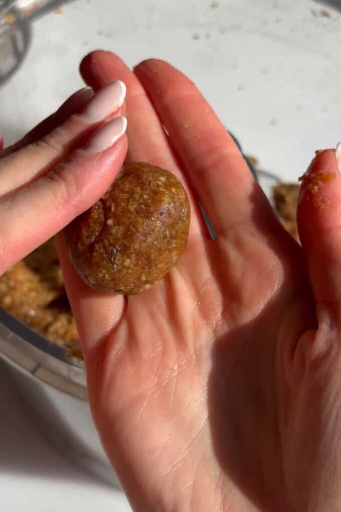 two hands rolling a carrot cake energy ball