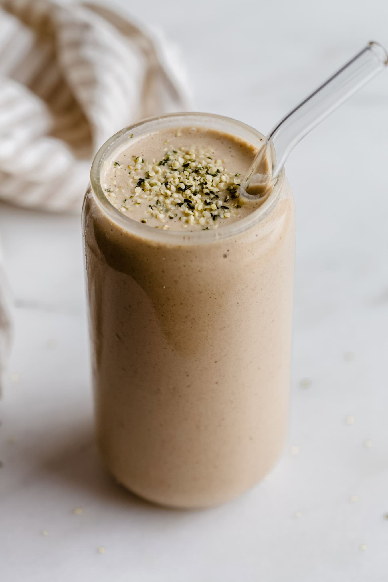 A glass of banana date smoothie topped with hemp seeds.