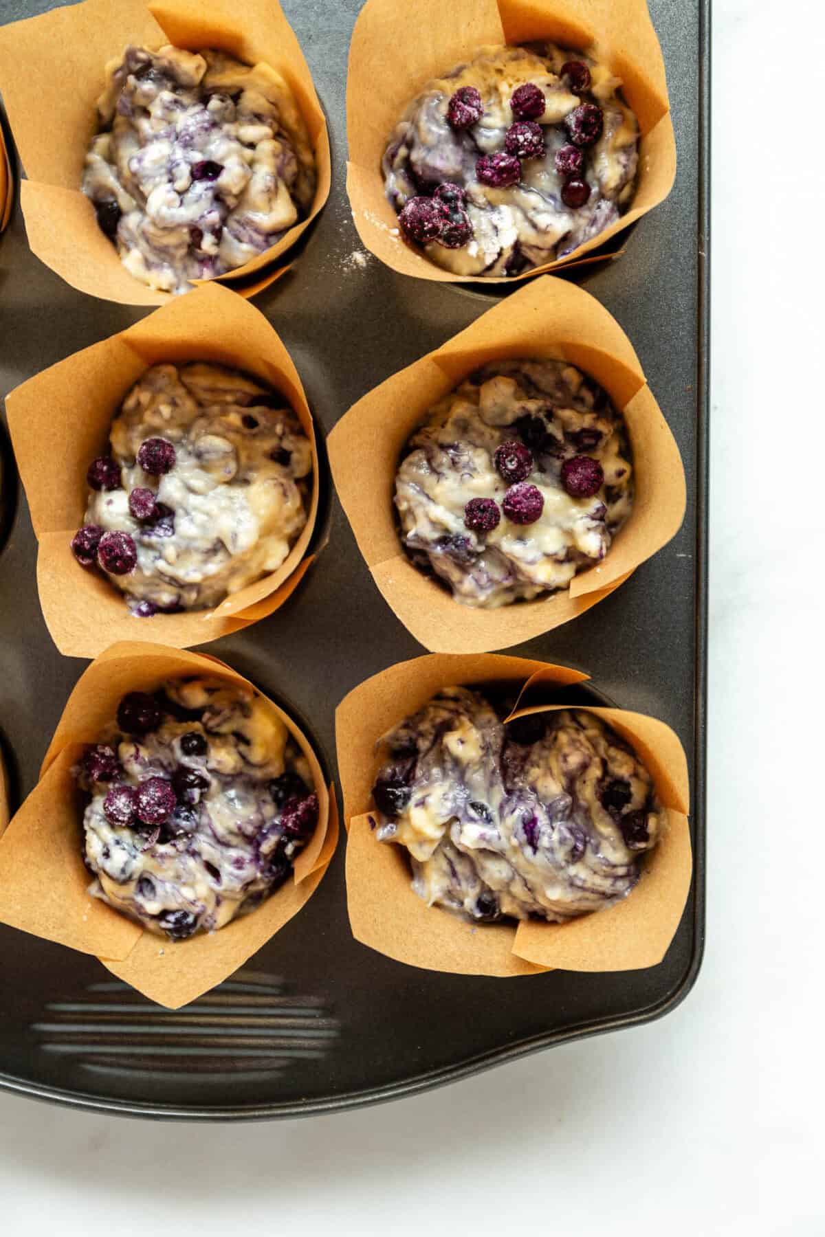 blueberry muffin batter in a muffin pan.