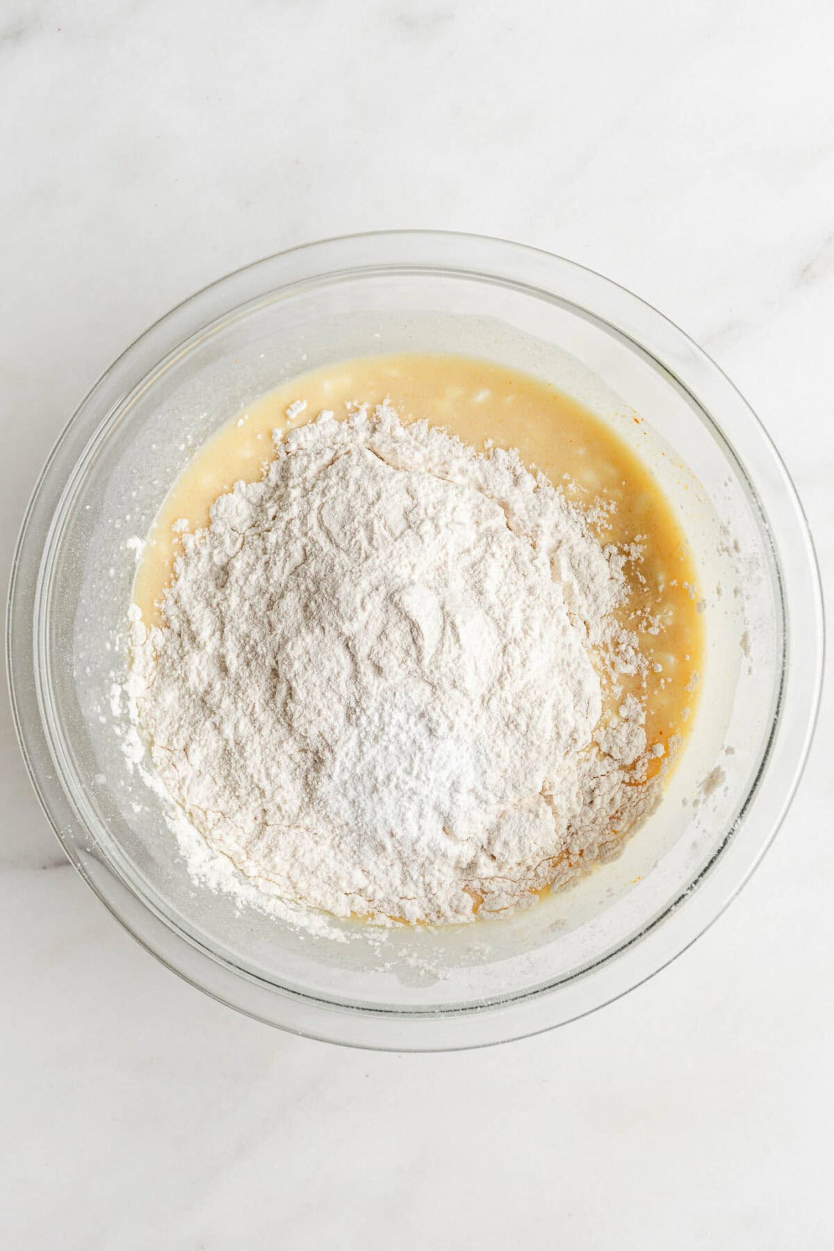 wet ingredients and flour in a mixing bowl to make blueberry muffins.