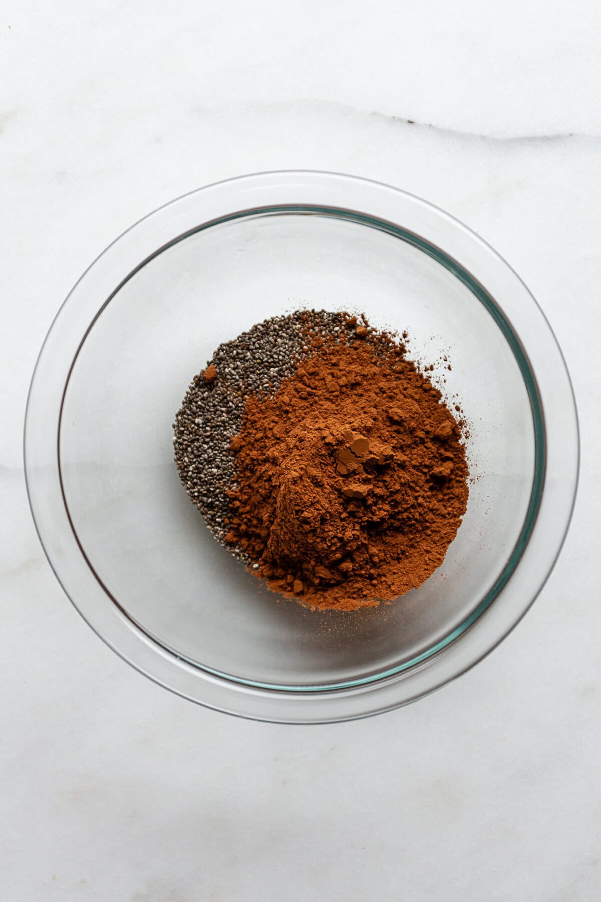 chia seeds and cocoa powder in a clear mixing bowl.
