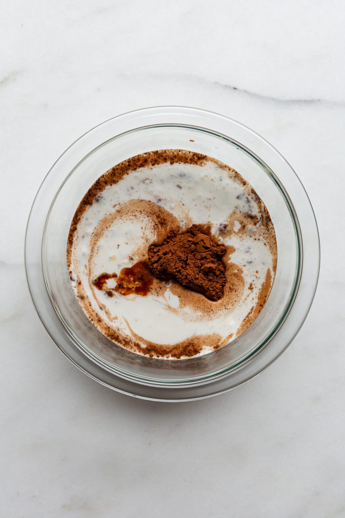 coconut milk, cocoa powder, vanilla extract, maple syrup and chia seeds in a clear mixing bowl.