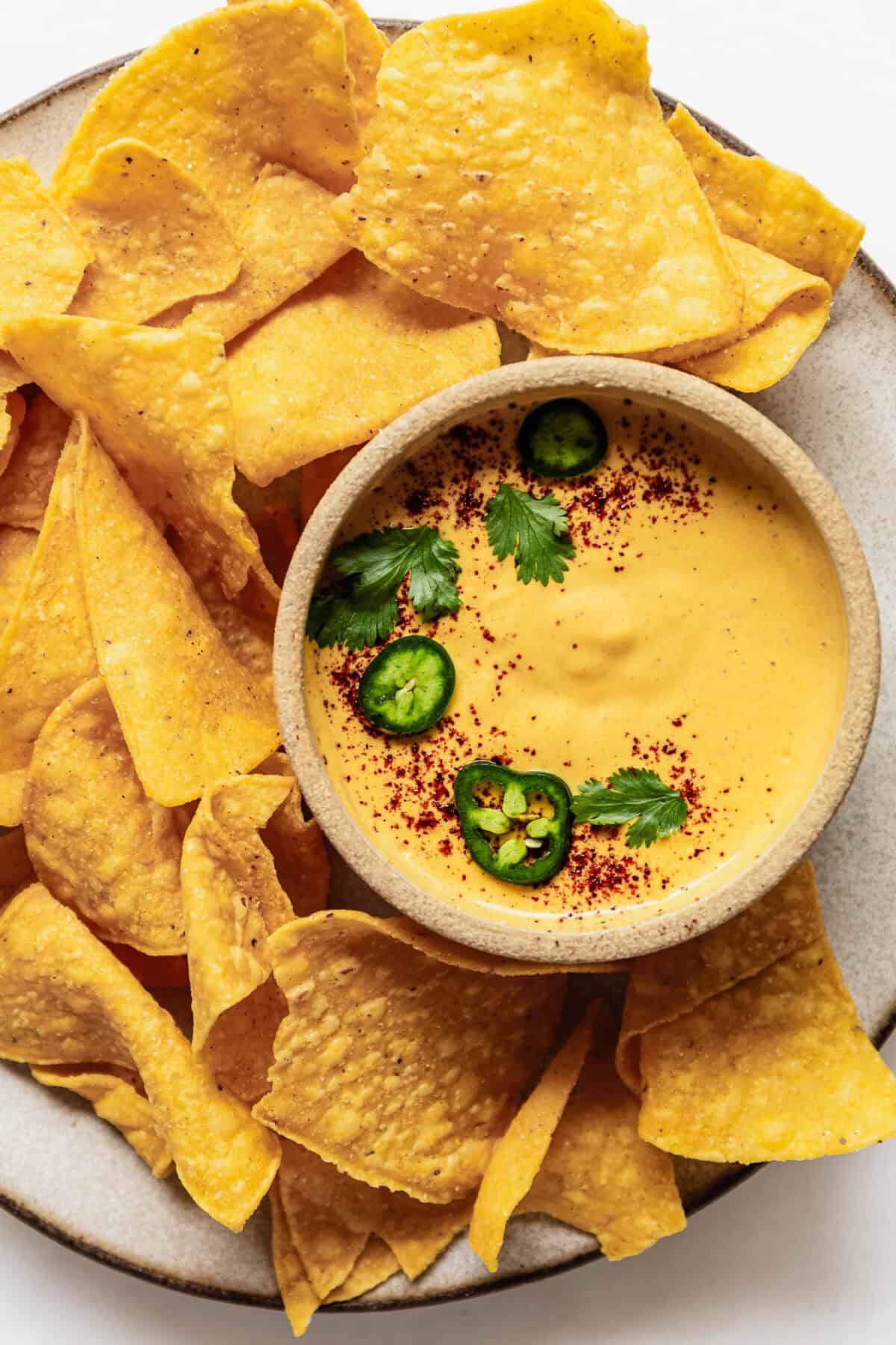 a small bowl of cottage cheese queso on a plate with tortilla chips.