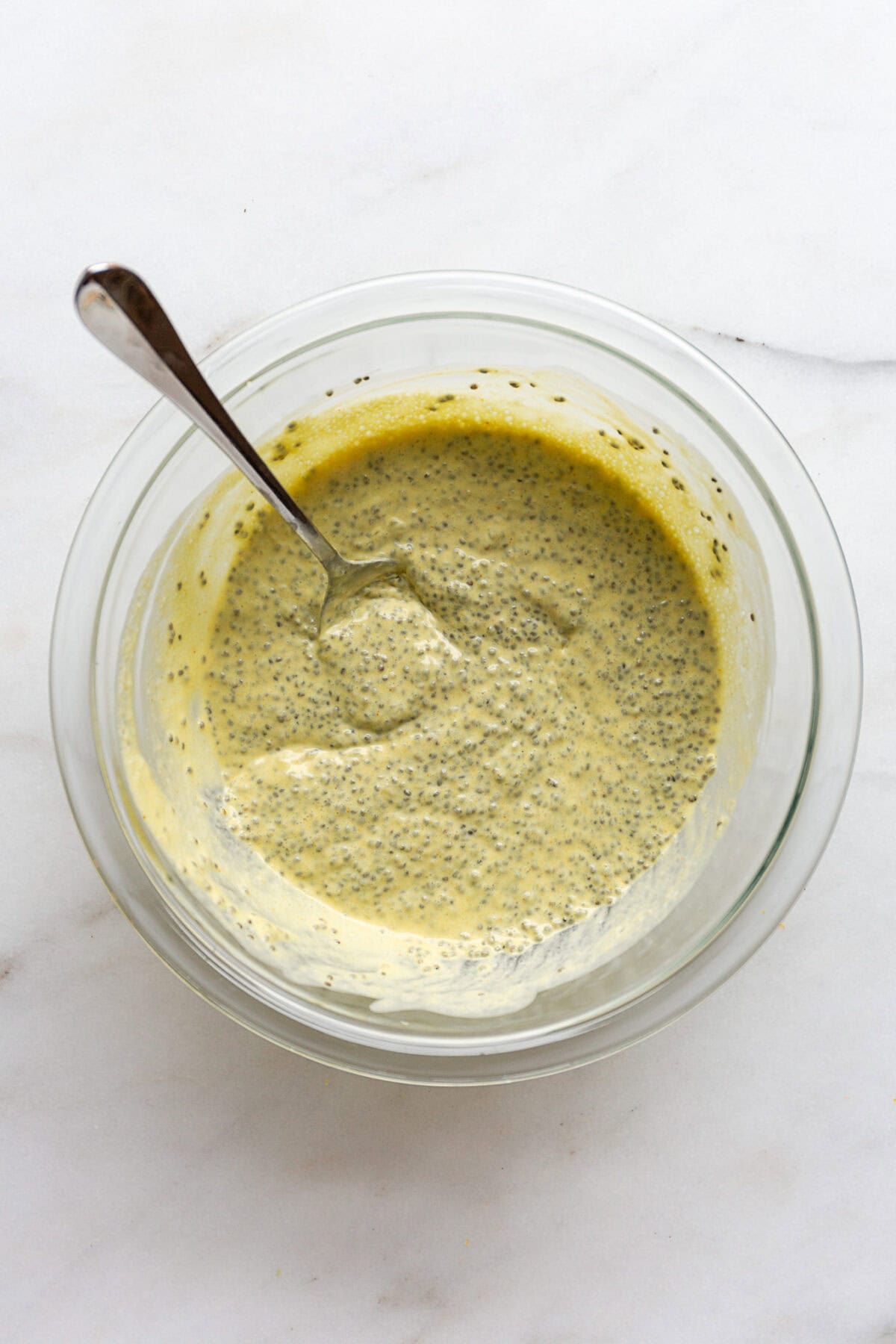 Lemon chia pudding in a mixing bowl with a spoon.