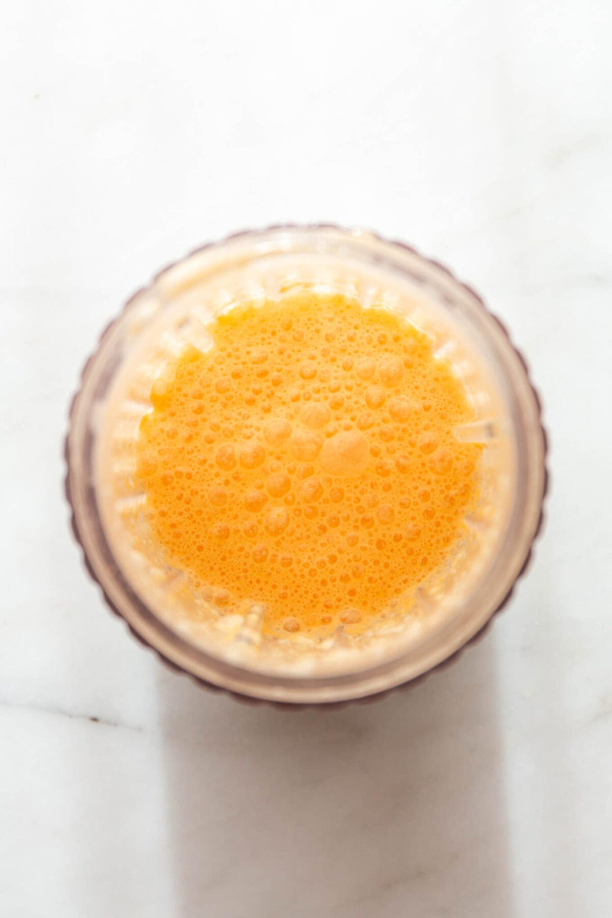 oranges, coconut milk, vanilla and maple syrup blended in a blender container.
