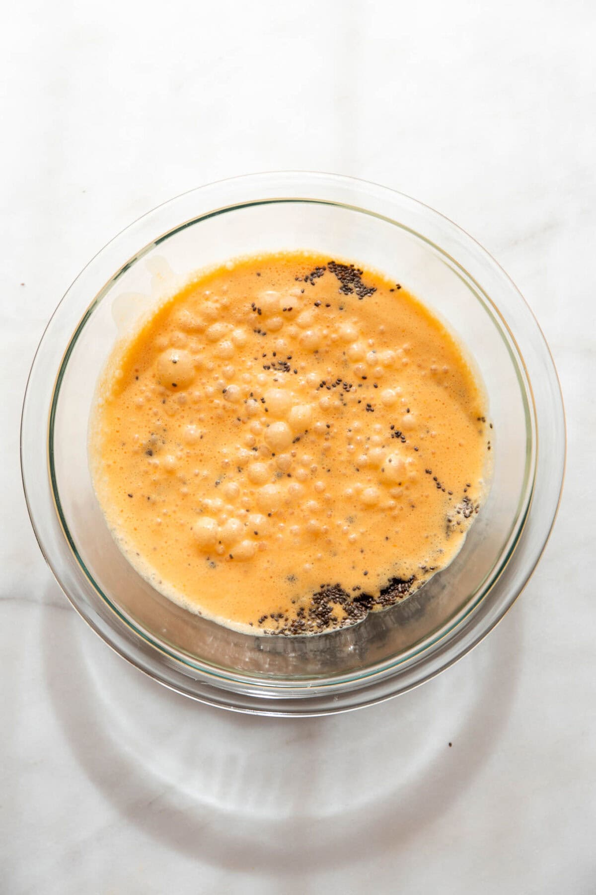 blended orange and coconut milk in a clear mixing bowl with chia seeds.
