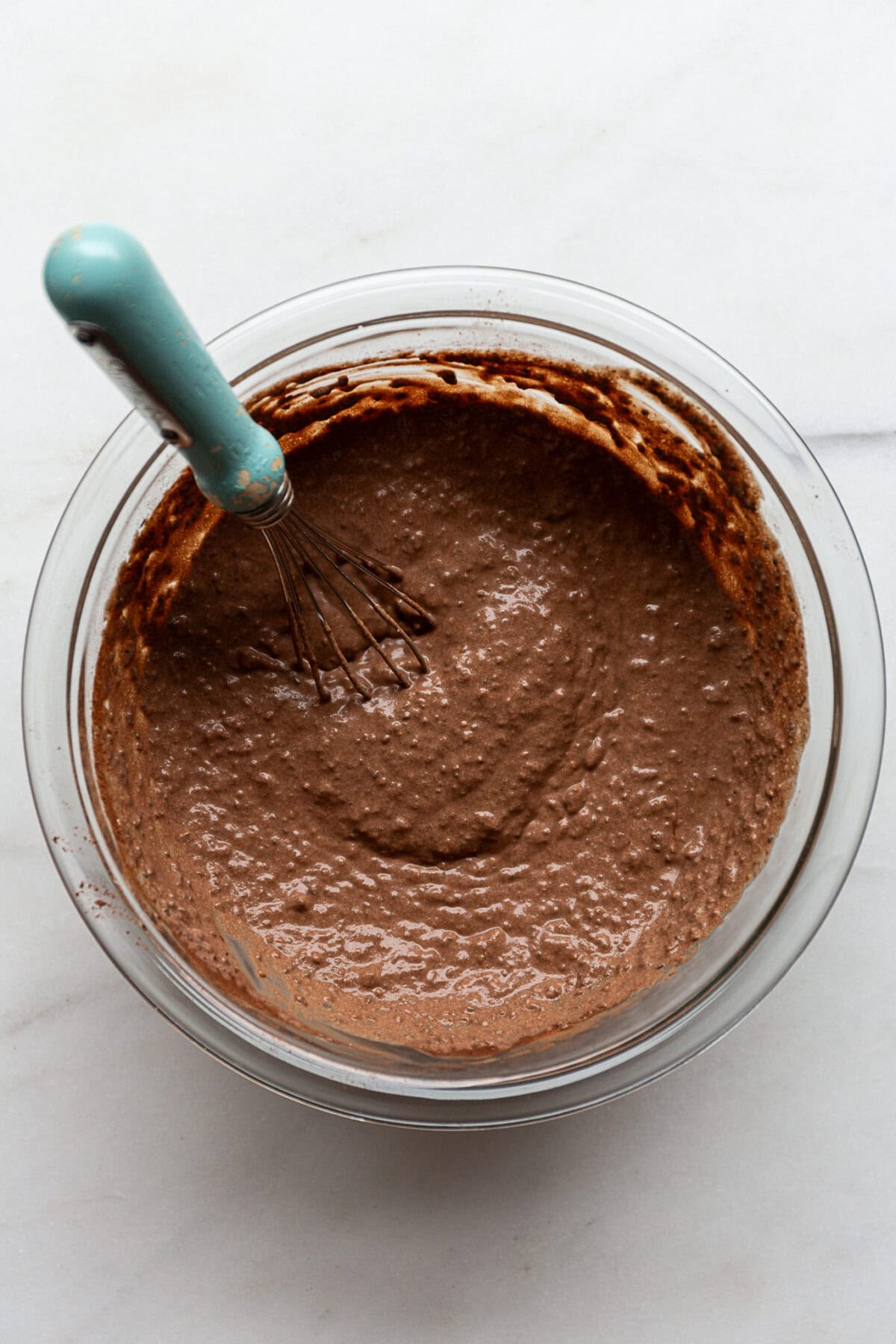 snickers chia pudding in a mixing bowl with a blue whisk in it.
