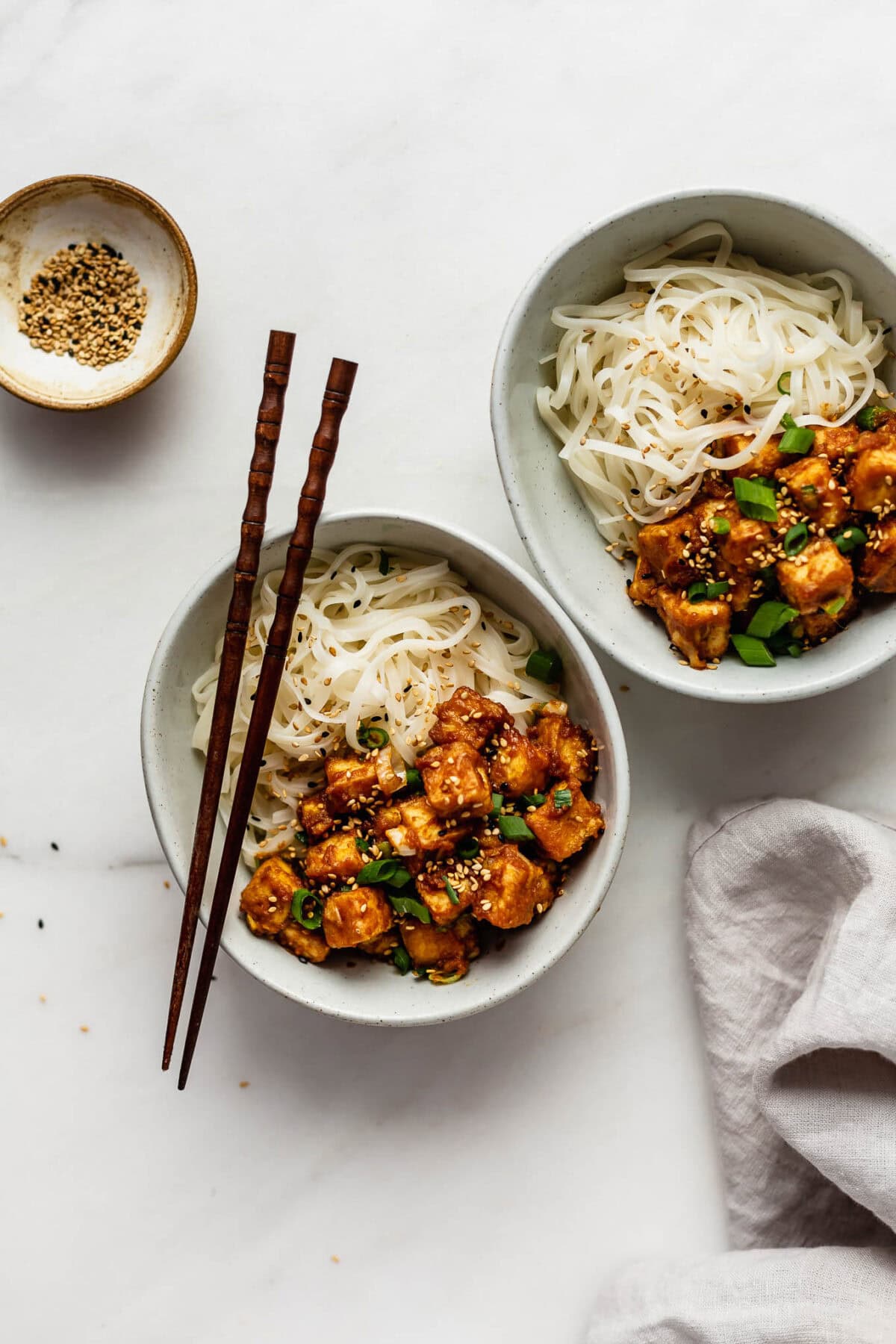 two bowls of peanut butter tofu and rice noodles.