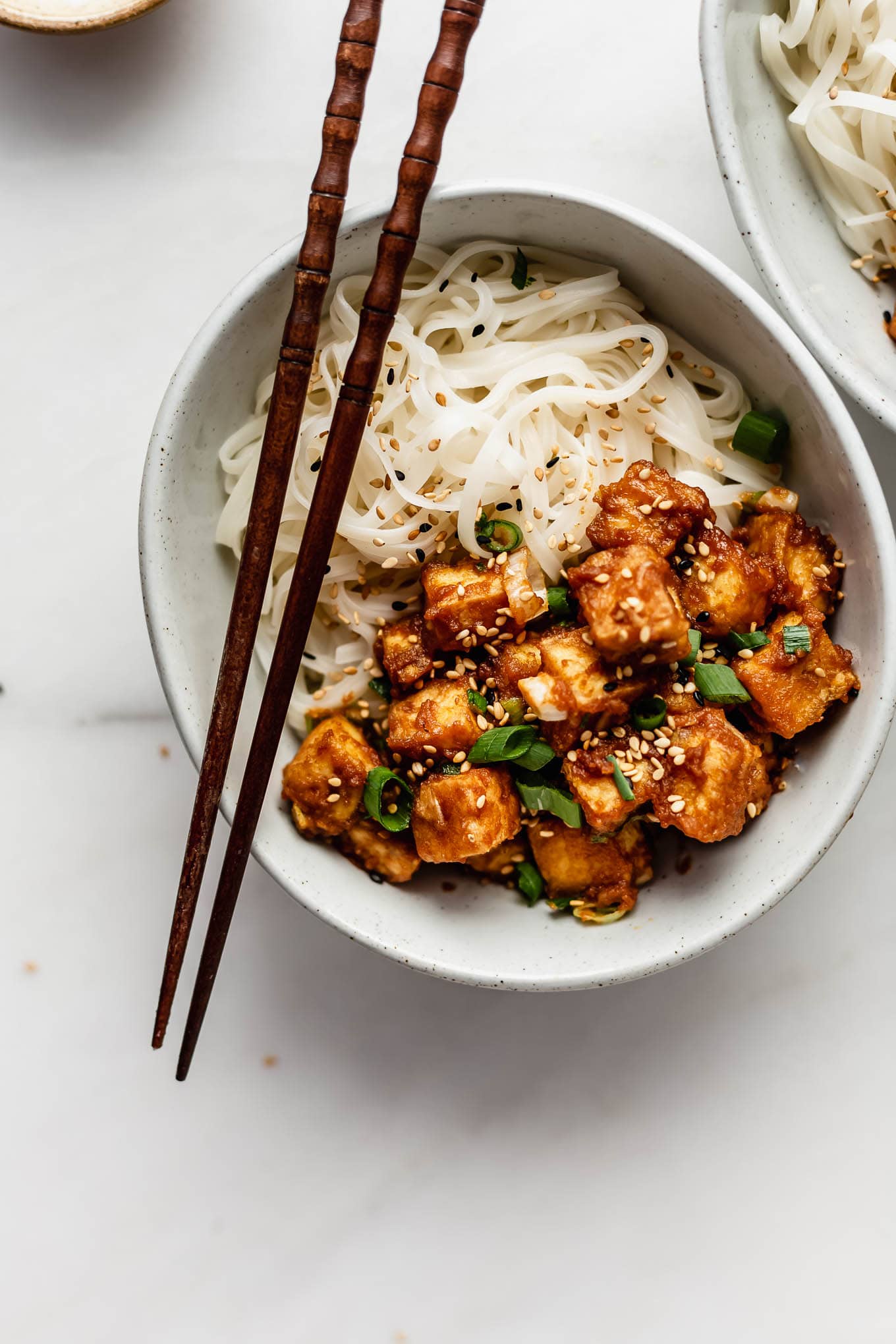 peanut butter tofu in a bowl with rice noodles.