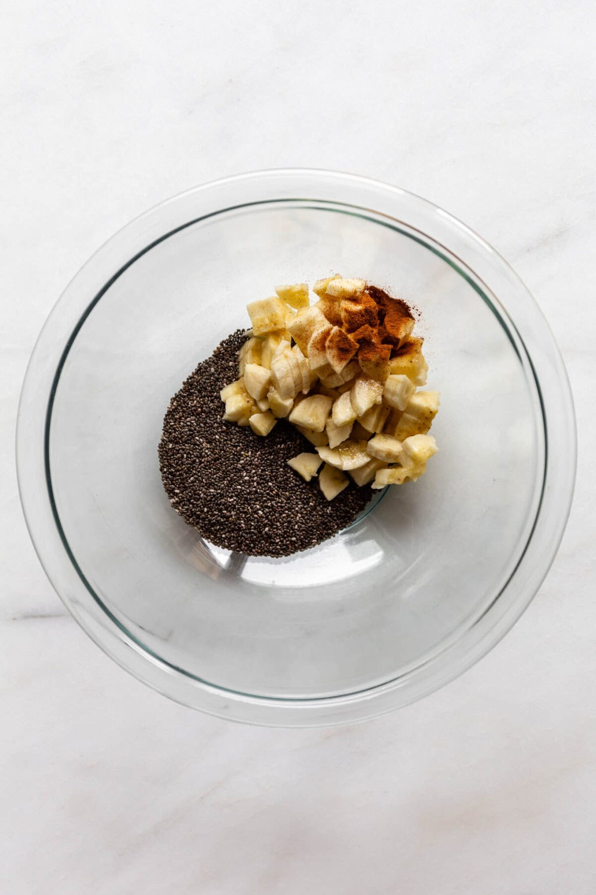 bananas, cinnamon and chia seeds in a clear bowl.