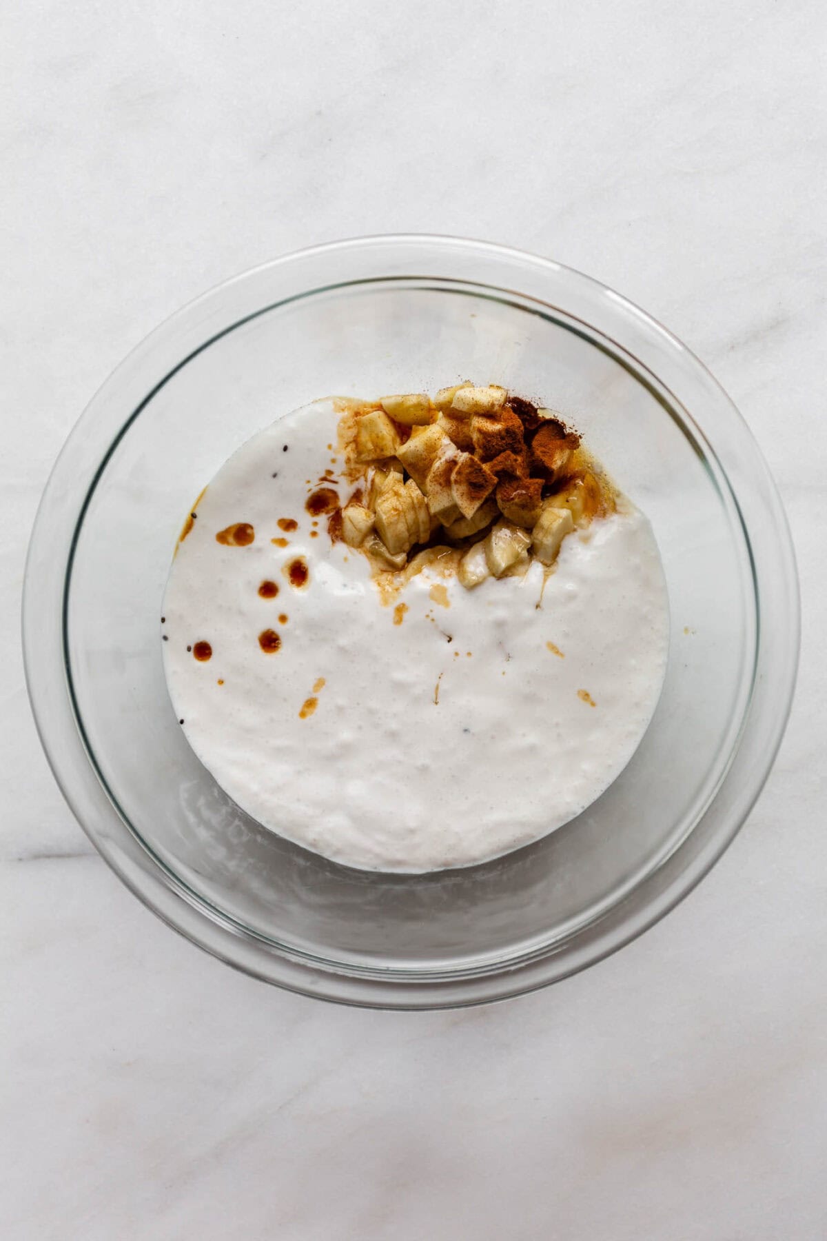 coconut milk, banana, maple syrup and cinnamon in a clear bowl.