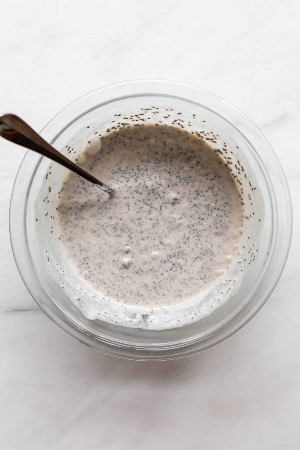 unset banana chia pudding in a mixing bowl with a spoon.