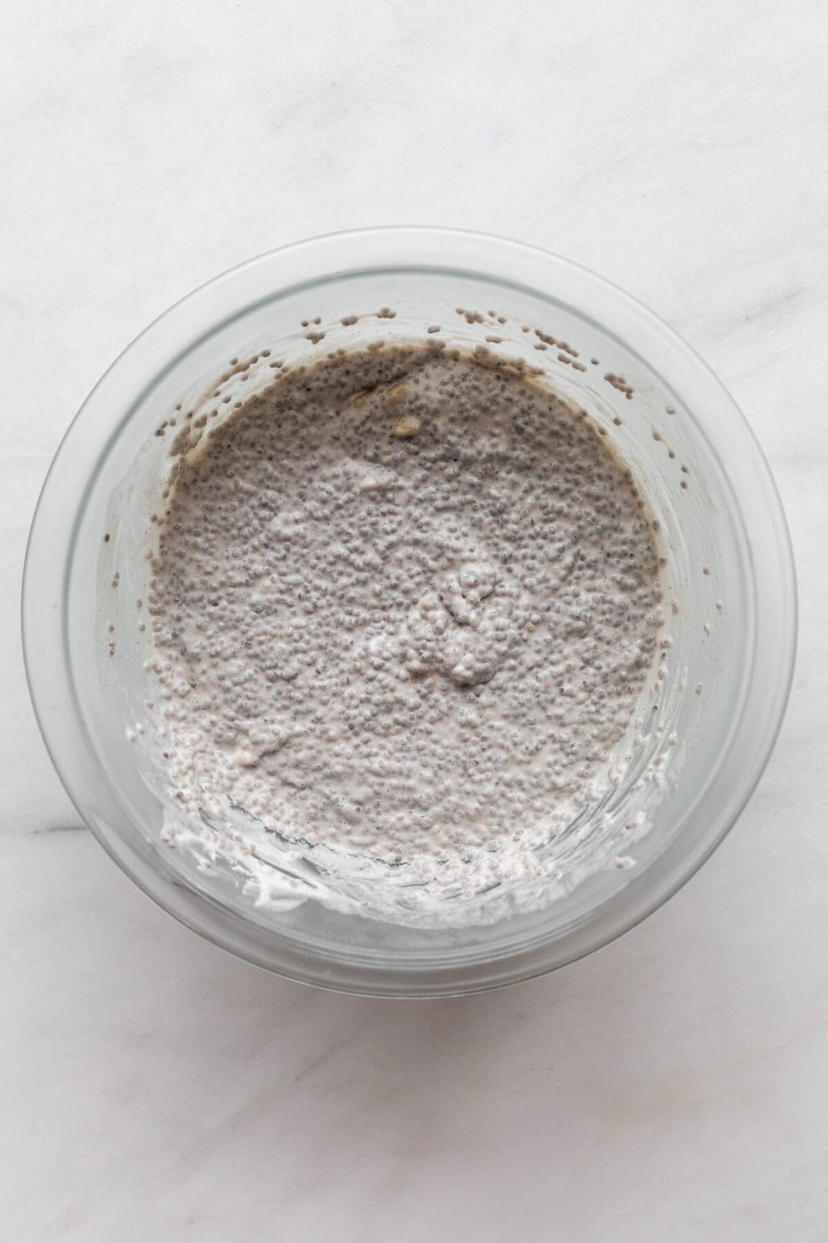 Banana chia pudding in a clear mixing bowl.
