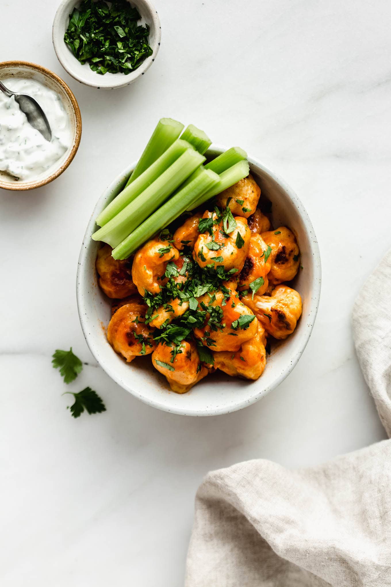 a bowl of buffalo cauliflower with a napkin on the side.