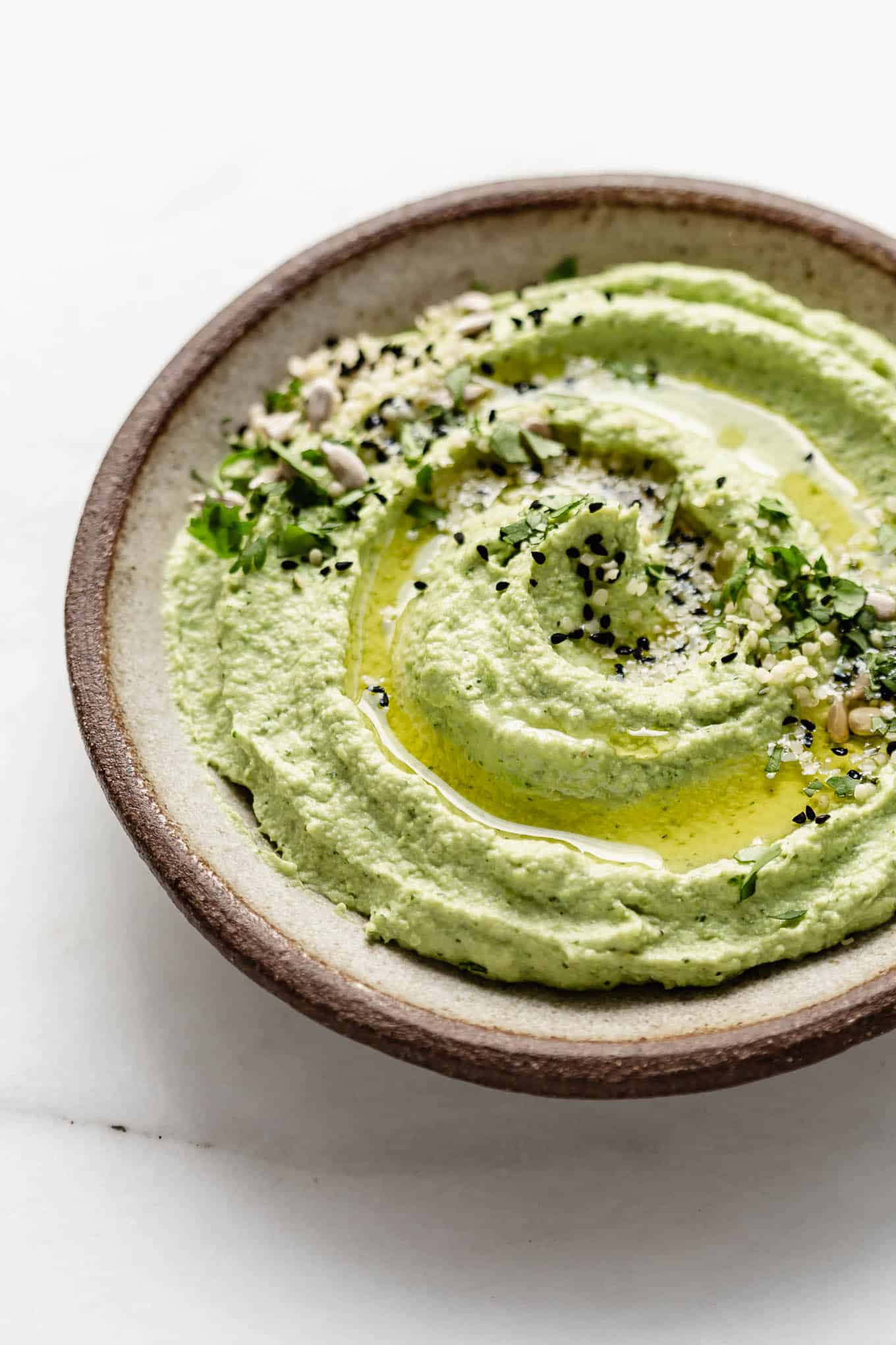 a dish of edamame hummus topped with olive oil.