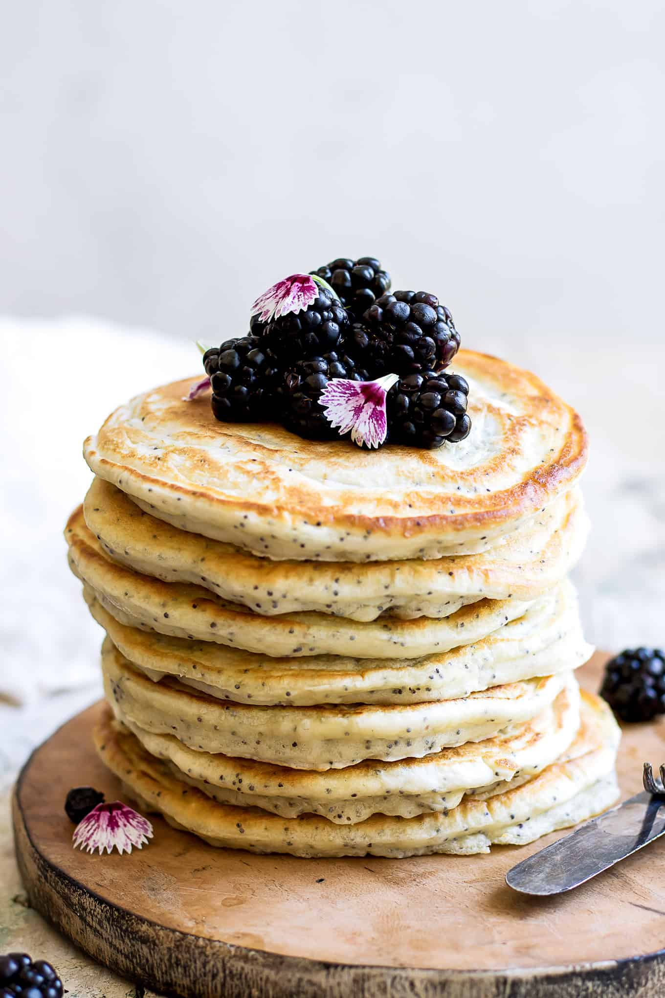 A stack of lemon poppyseed pancakes topped with blackberries.